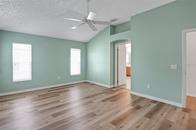 empty room featuring wood-type flooring, ceiling fan, vaulted ceiling, and a textured ceiling