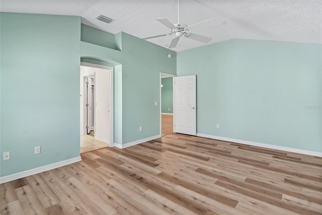 empty room featuring a textured ceiling, high vaulted ceiling, ceiling fan, and light wood-type flooring