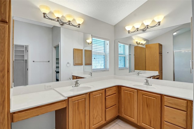 bathroom with dual sinks, large vanity, tile floors, and a textured ceiling