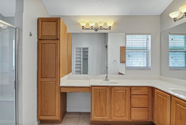 bathroom featuring vanity, tile floors, a shower with shower door, and a textured ceiling