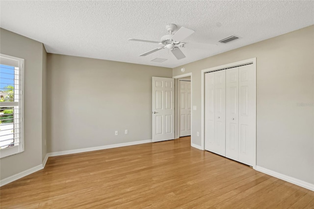 unfurnished bedroom featuring light hardwood / wood-style floors, ceiling fan, and a textured ceiling