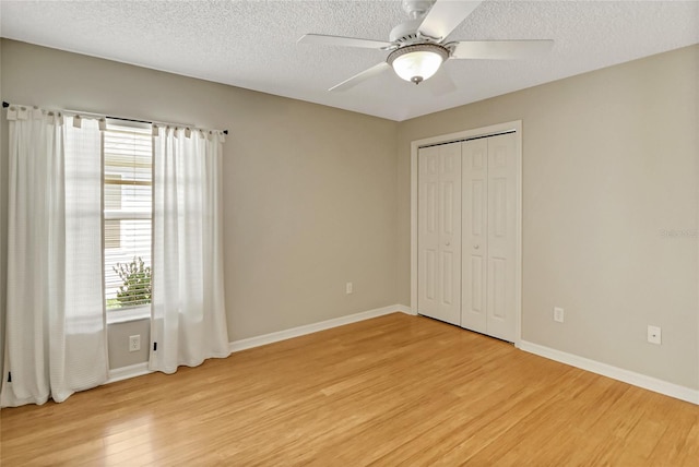 unfurnished bedroom with a closet, ceiling fan, light wood-type flooring, and a textured ceiling