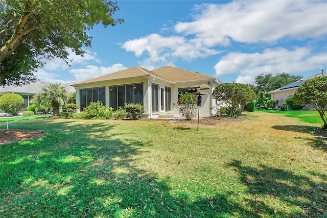 rear view of house with a sunroom and a lawn