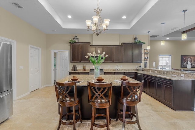 kitchen featuring appliances with stainless steel finishes, a raised ceiling, pendant lighting, and light stone countertops