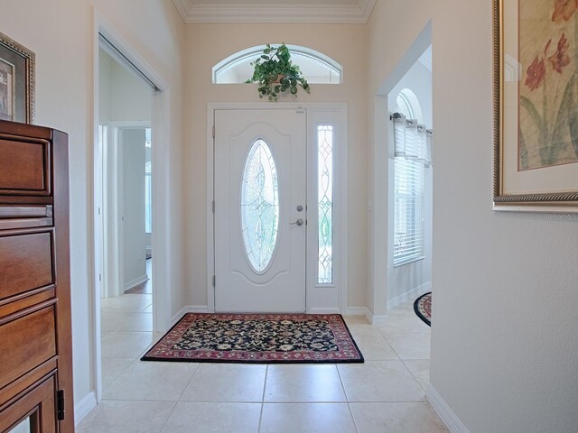 entryway featuring a wealth of natural light, light tile patterned floors, baseboards, and crown molding