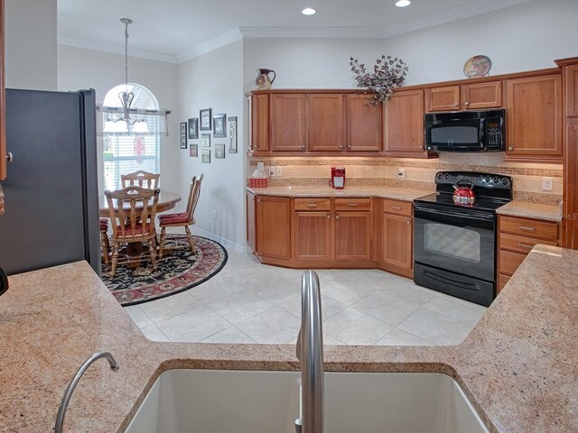 kitchen with pendant lighting, light tile patterned floors, decorative backsplash, a sink, and black appliances