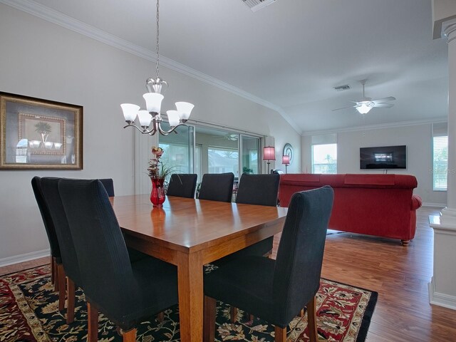 dining room with baseboards, visible vents, wood finished floors, vaulted ceiling, and crown molding