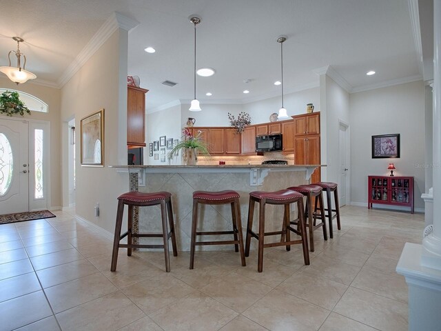 kitchen with black microwave, hanging light fixtures, brown cabinetry, and visible vents