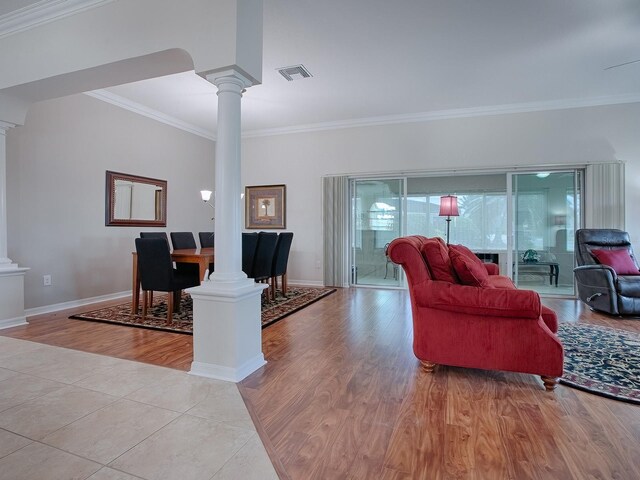 living room with decorative columns, visible vents, and light wood-style flooring