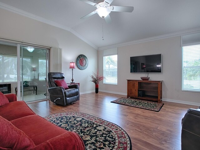 living room featuring lofted ceiling, light wood finished floors, ornamental molding, and a wealth of natural light