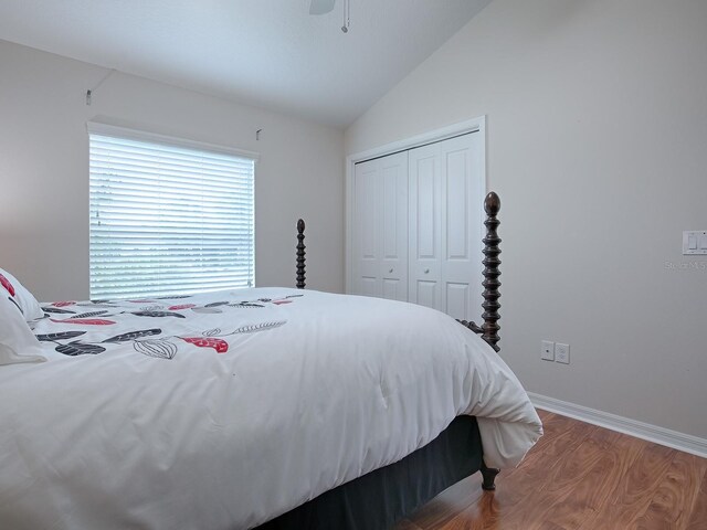 bedroom with lofted ceiling, a closet, a ceiling fan, wood finished floors, and baseboards