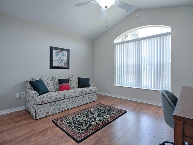 living room with lofted ceiling, ceiling fan, a textured ceiling, wood finished floors, and baseboards