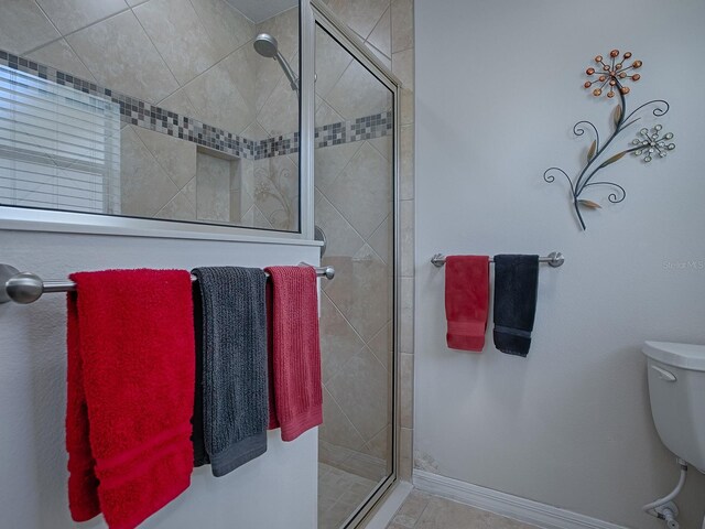 bathroom with a stall shower, baseboards, and toilet