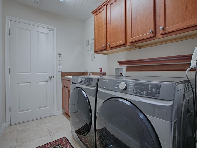 laundry room with cabinet space, baseboards, washing machine and clothes dryer, a textured ceiling, and light tile patterned flooring