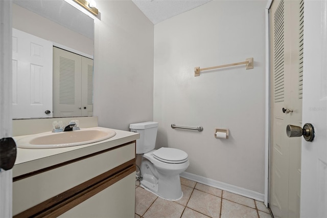 bathroom with a textured ceiling, tile patterned flooring, vanity, and toilet