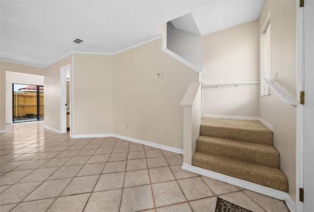 stairway featuring crown molding and tile patterned floors