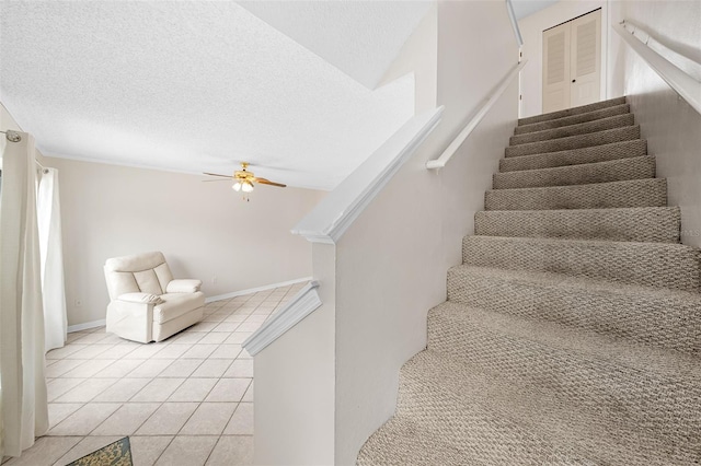 staircase with tile patterned flooring, ceiling fan, and a textured ceiling