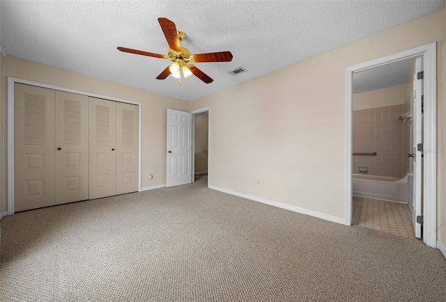 unfurnished bedroom with ceiling fan, ensuite bathroom, a closet, and carpet flooring