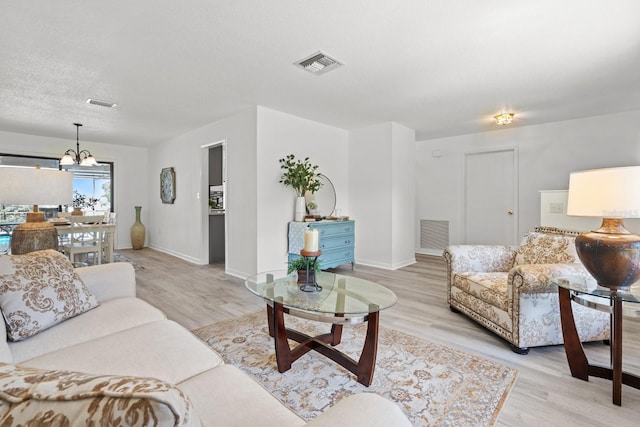 living room featuring a chandelier, a textured ceiling, and light hardwood / wood-style flooring