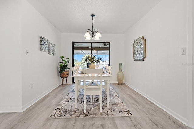 dining area with light wood-type flooring, a textured ceiling, and a chandelier