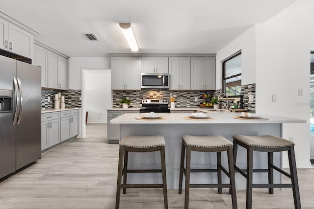 kitchen with light wood-type flooring, stainless steel appliances, and gray cabinetry