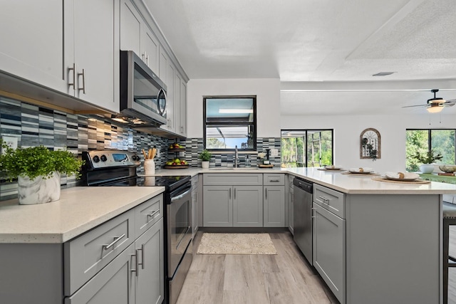 kitchen with plenty of natural light, kitchen peninsula, sink, and appliances with stainless steel finishes