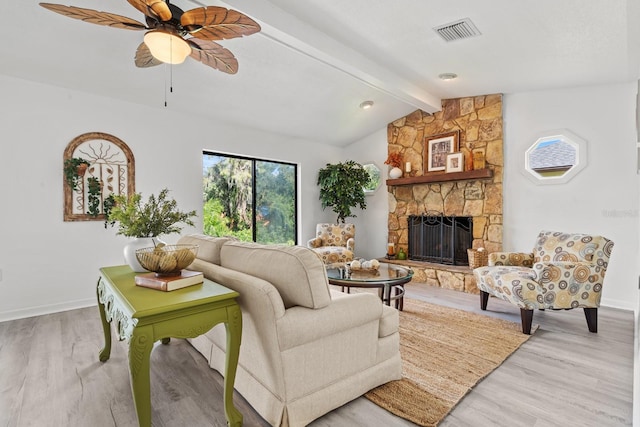 living room with lofted ceiling with beams, light hardwood / wood-style flooring, ceiling fan, and a stone fireplace