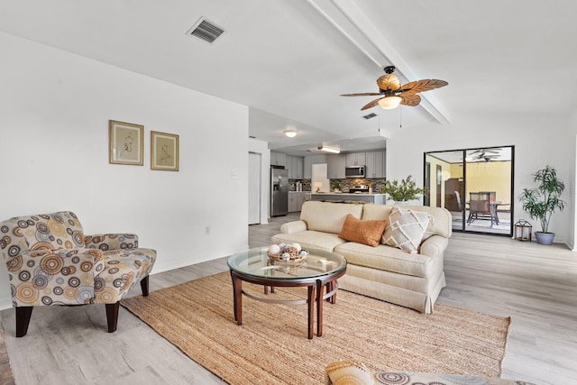 living room with vaulted ceiling with beams, ceiling fan, and light hardwood / wood-style flooring