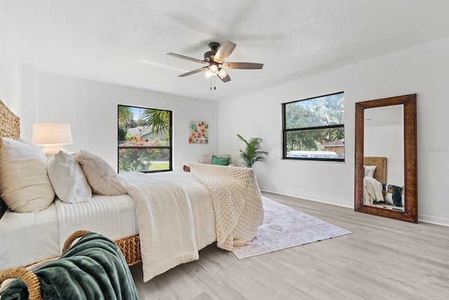 bedroom featuring hardwood / wood-style floors, ceiling fan, and a textured ceiling