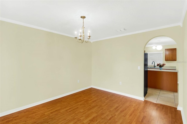 unfurnished room with light hardwood / wood-style floors, crown molding, a chandelier, and sink