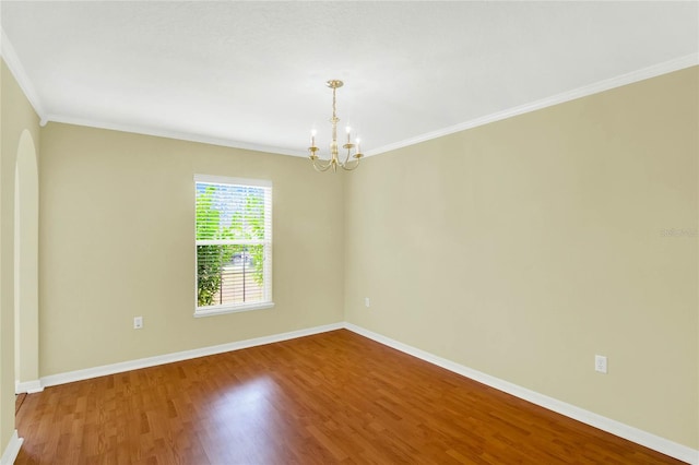 spare room with crown molding, wood-type flooring, and an inviting chandelier