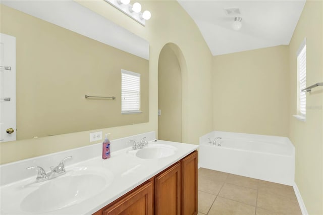 bathroom featuring vanity, lofted ceiling, a tub to relax in, and tile patterned floors