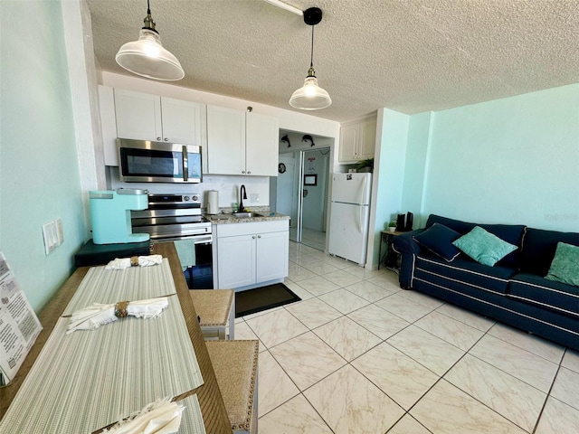 kitchen featuring appliances with stainless steel finishes, white cabinets, light tile floors, and hanging light fixtures