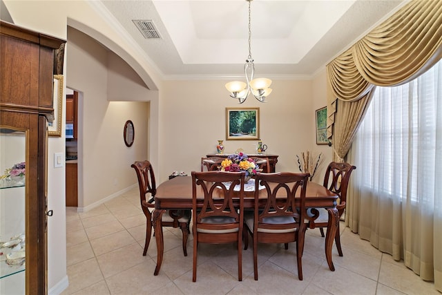 tiled dining room with a notable chandelier, a raised ceiling, and crown molding