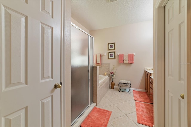 bathroom with a textured ceiling, shower with separate bathtub, tile patterned flooring, and vanity