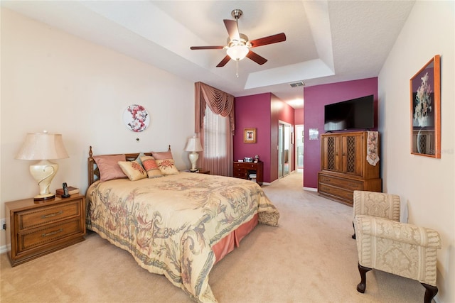 carpeted bedroom with a tray ceiling and ceiling fan