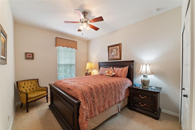 carpeted bedroom featuring ceiling fan and a textured ceiling