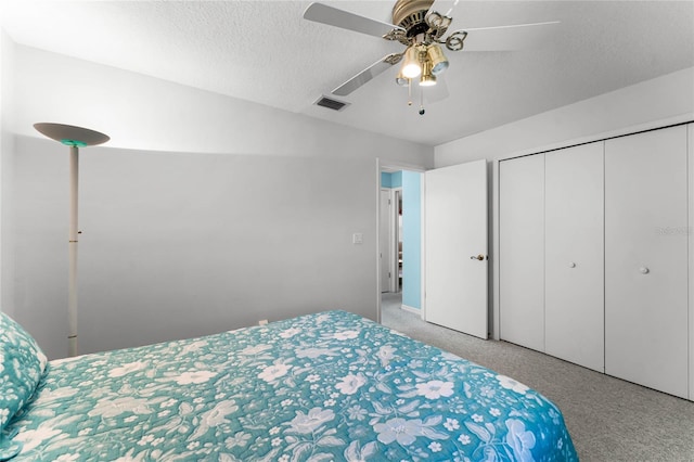 bedroom featuring ceiling fan, a closet, a textured ceiling, and light colored carpet