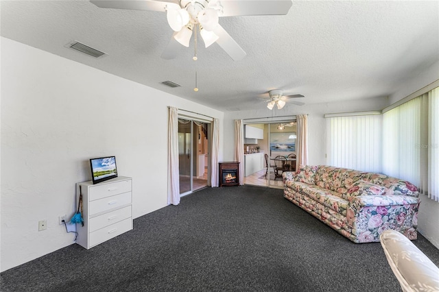 carpeted living room featuring ceiling fan and a textured ceiling