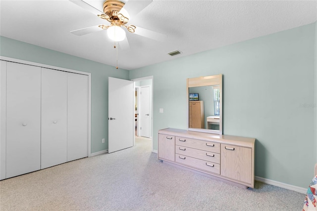 bedroom with light carpet, a closet, ceiling fan, and a textured ceiling