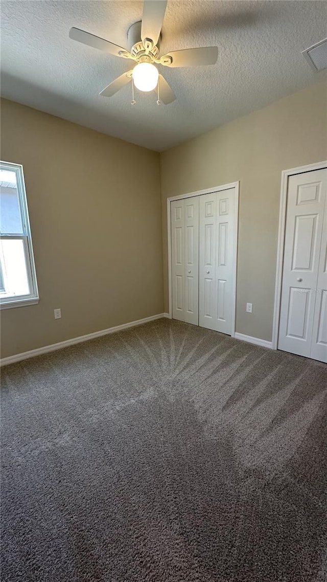 unfurnished bedroom with a textured ceiling, carpet flooring, and ceiling fan