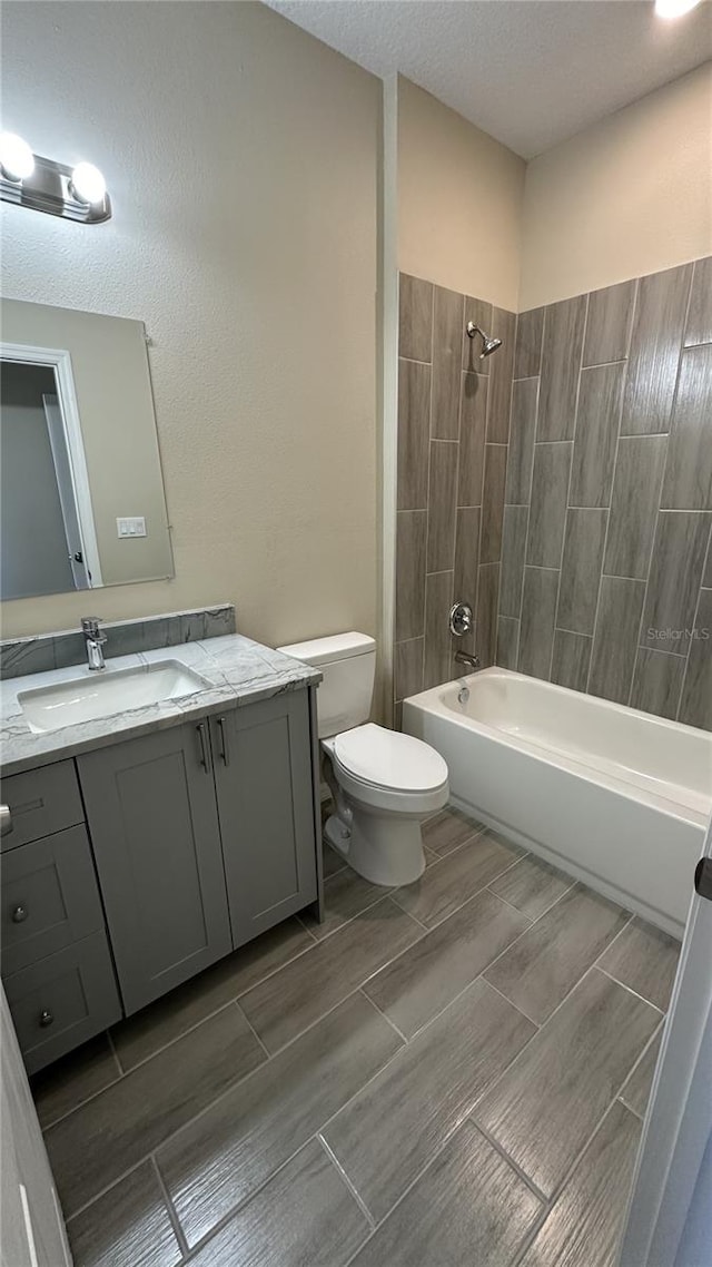 full bathroom featuring tiled shower / bath, vanity, toilet, and tile floors