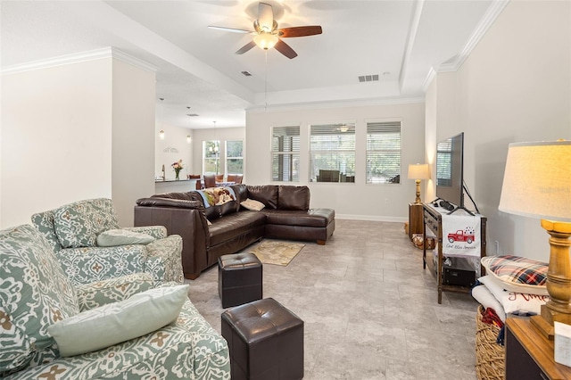 tiled living room featuring ceiling fan, a tray ceiling, and crown molding