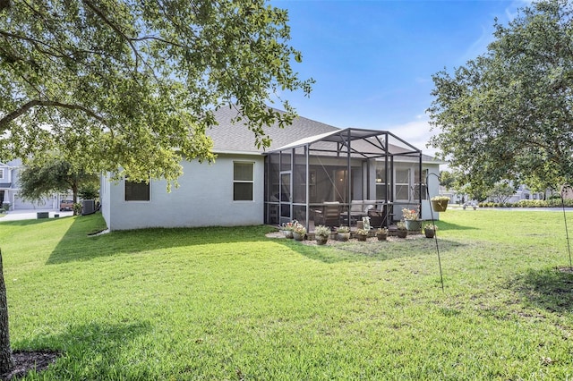 back of property with glass enclosure and a yard