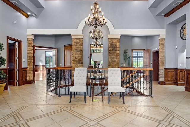 kitchen with ornate columns, a chandelier, beam ceiling, and light tile floors