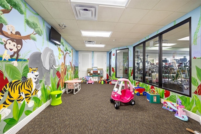 playroom with carpet floors and a paneled ceiling