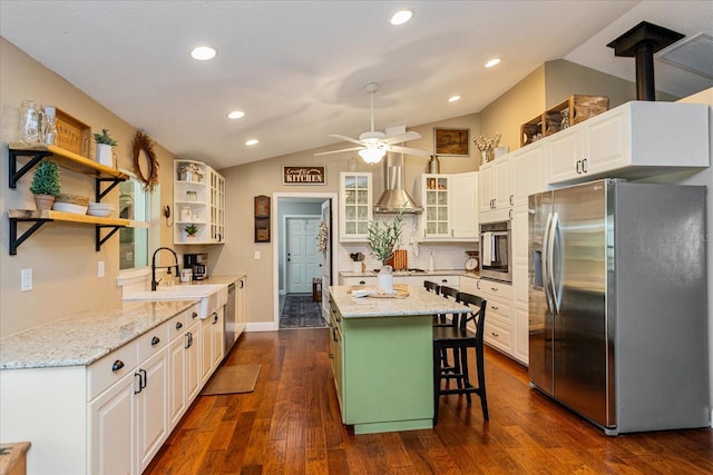 kitchen featuring sink, appliances with stainless steel finishes, white cabinetry, a kitchen breakfast bar, and vaulted ceiling