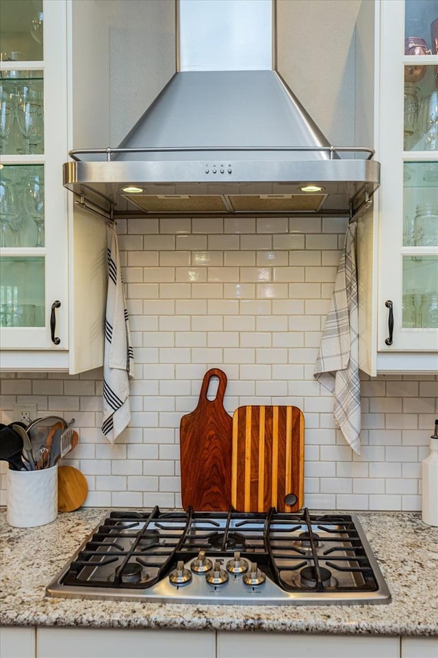 kitchen featuring stainless steel gas stovetop, light stone countertops, white cabinets, and island exhaust hood