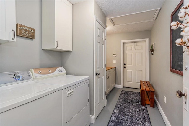 clothes washing area featuring washer and dryer, cabinets, and a textured ceiling