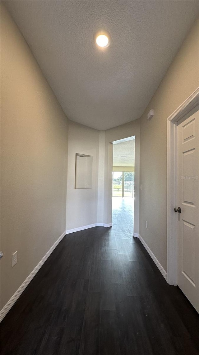 unfurnished room featuring a textured ceiling and dark wood-type flooring